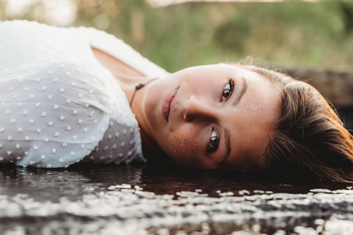 Creative high school senior portrait featuring a girl with gold face glitter reflecting in water during a Branson, MO photo session.