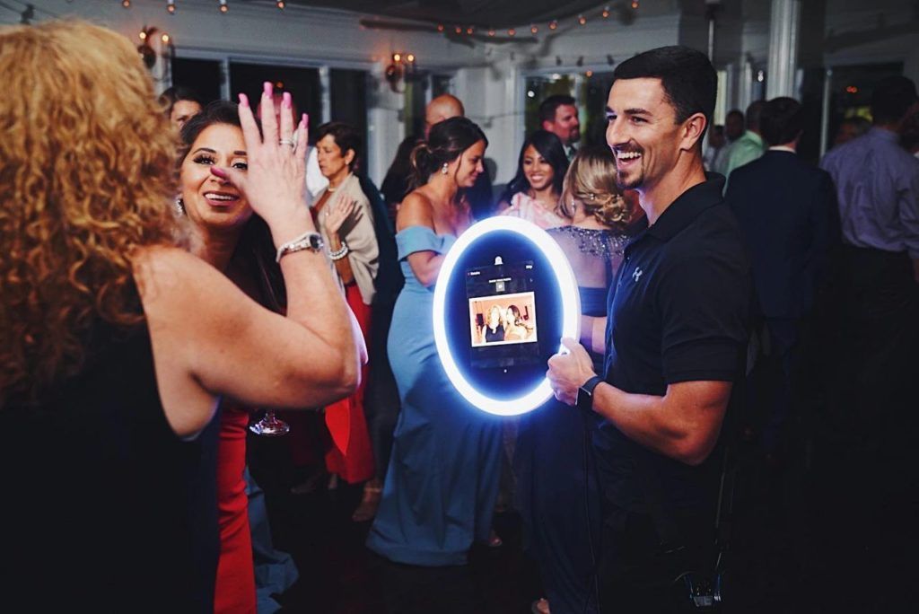 People dancing and enjoying music at a crowded  party with blue neon lighting effects roaming Booth in Miami