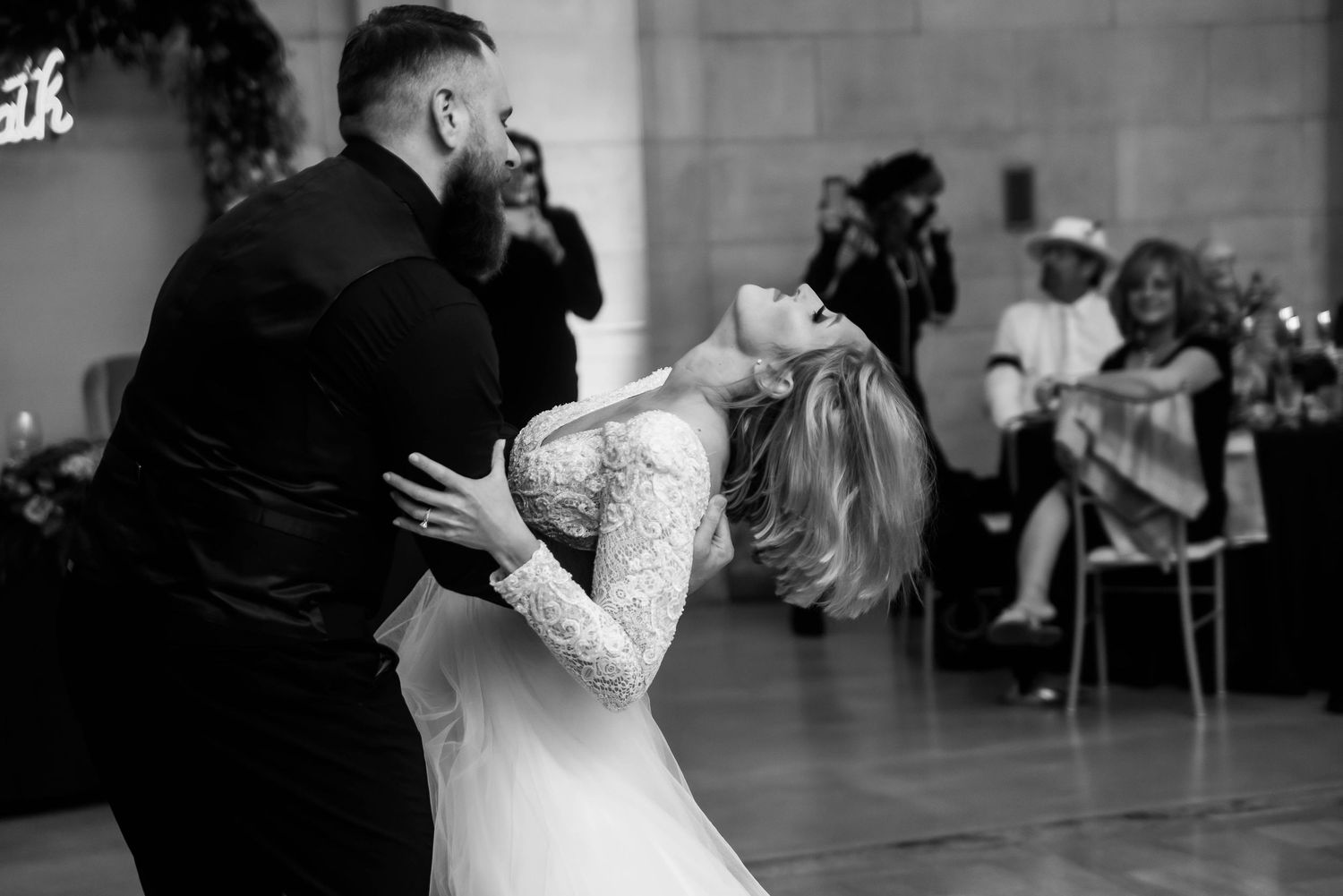 A romantic dance scene unfolds in a dimly lit reception hall with guests looking on in Cleveland, Ohio.
