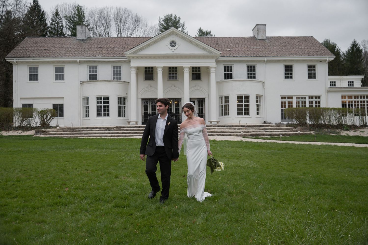 A grand white colonial-style mansion serves as an elegant backdrop for a wedding celebration in Youngstown, Ohio.