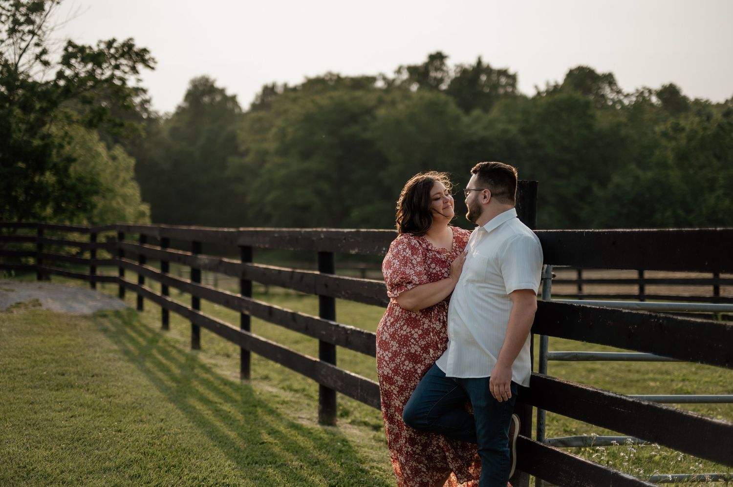 Romantic sunset portrait of a couple standing by wooden fence at a rustic farm in North Lawrence, Ohio.
