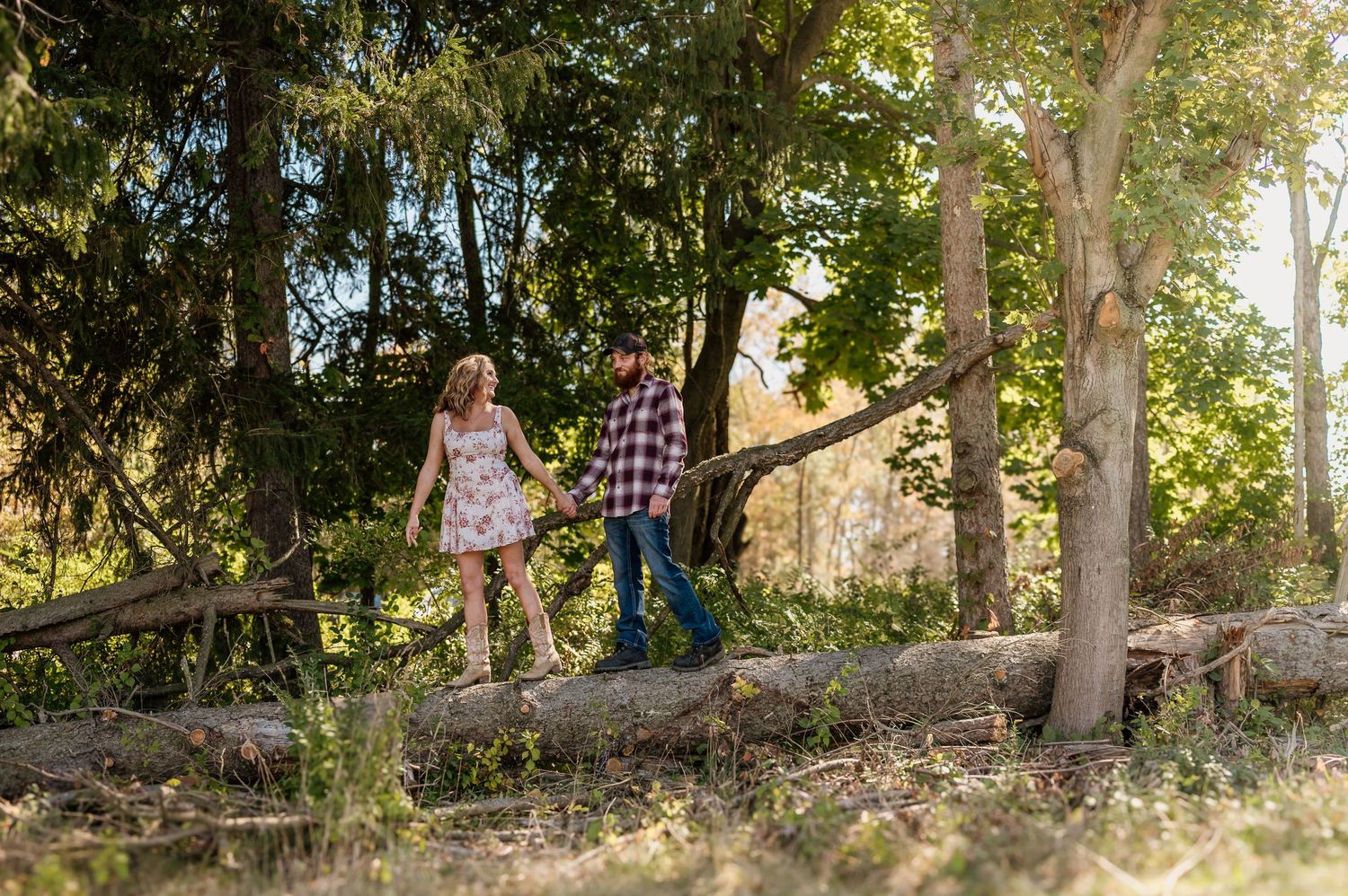 A couple enjoy a sunny day in a wooded area with scattered rocks and dappled sunlight filtering through the trees in Hartville, Ohio.