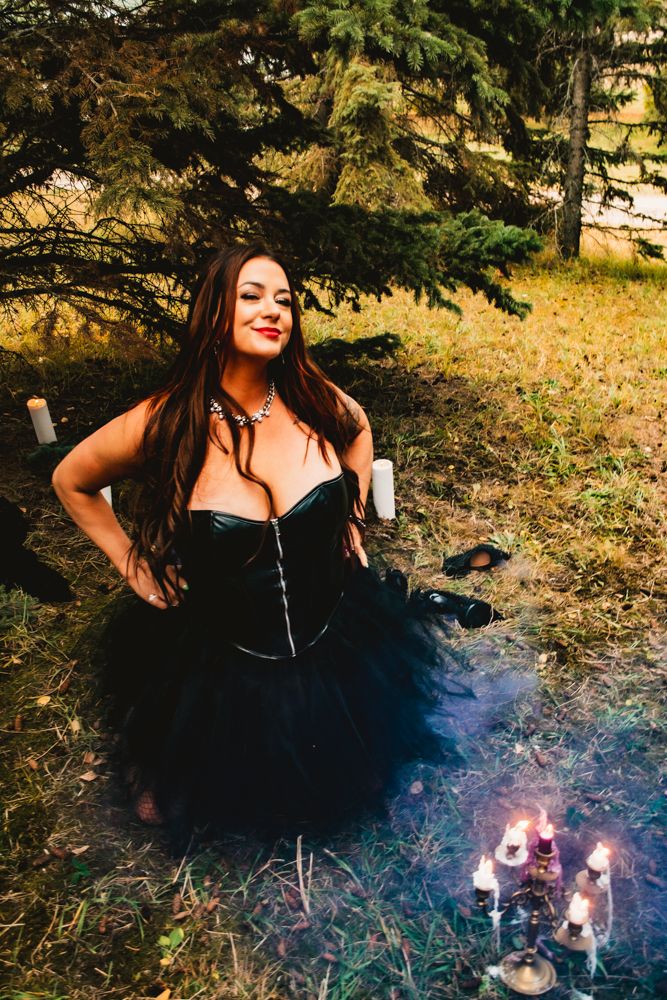 Gothic styled portrait with black corset dress and smoke effects near lit candles.