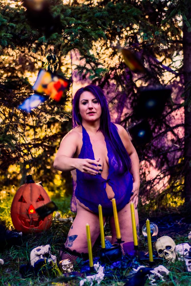 Halloween scene with decorative skulls, candles, and pumpkins in forest setting.