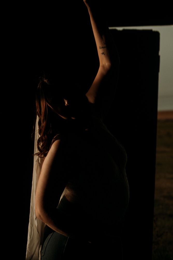 Artistic silhouette of a person reaching upward in moody lighting against a dark backdrop.