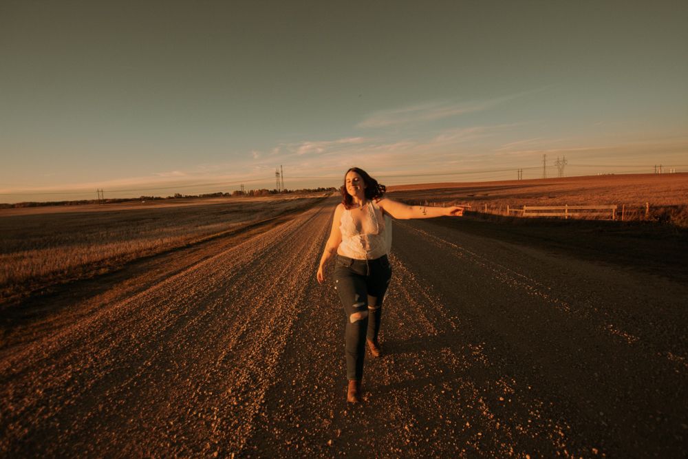 Dancing figure on empty country road during golden hour.