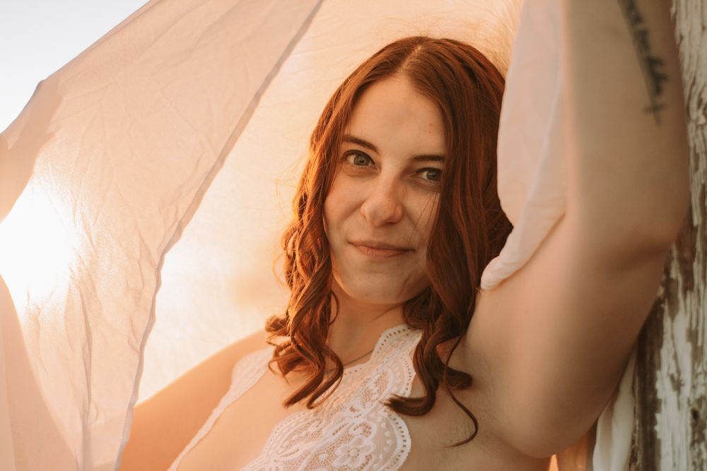 Intimate portrait with soft natural lighting and flowing fabric creating warm tones.