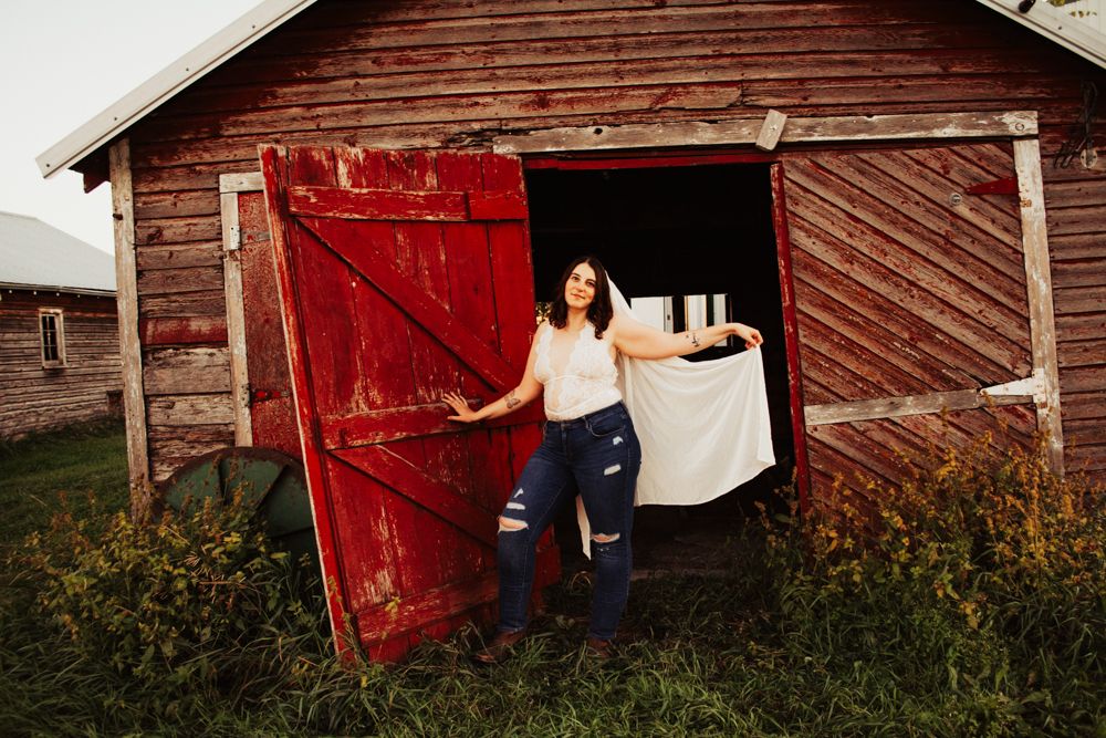 Portrait in front of weathered red barn door with white fabric detail.