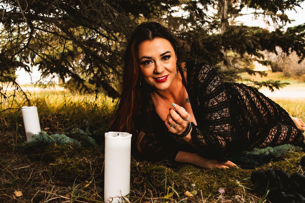 Elegant outdoor scene with lace outfit and white pillar candles under pine trees.