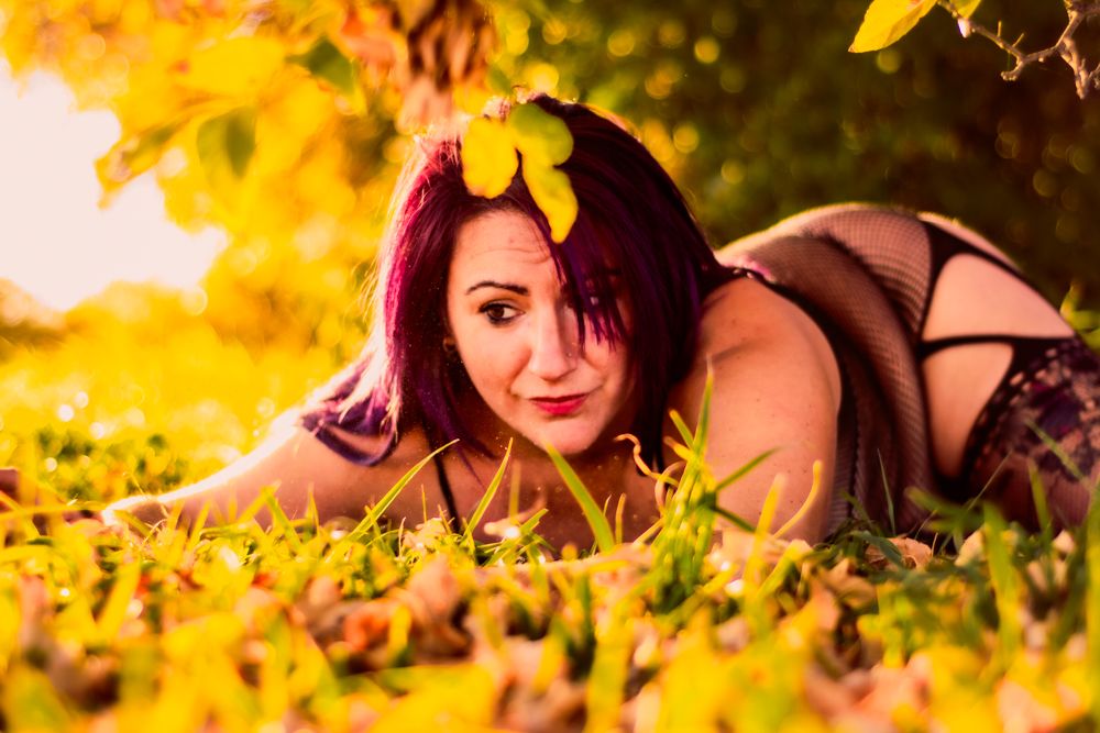 Artistic intimate portrait in warm golden autumn lighting with yellow leaves.