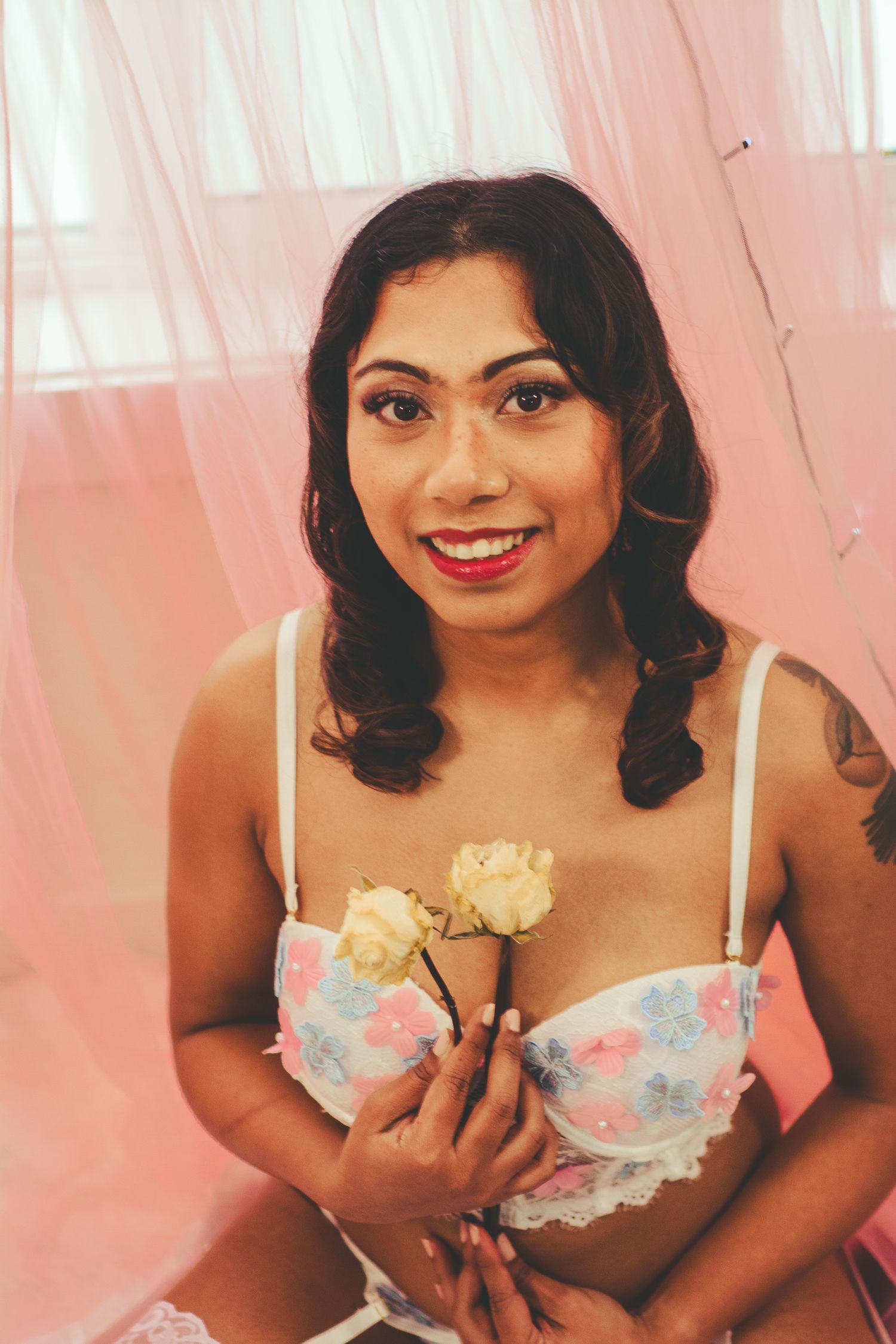 Boudoir photo showing floral lingerie and roses with natural window lighting.