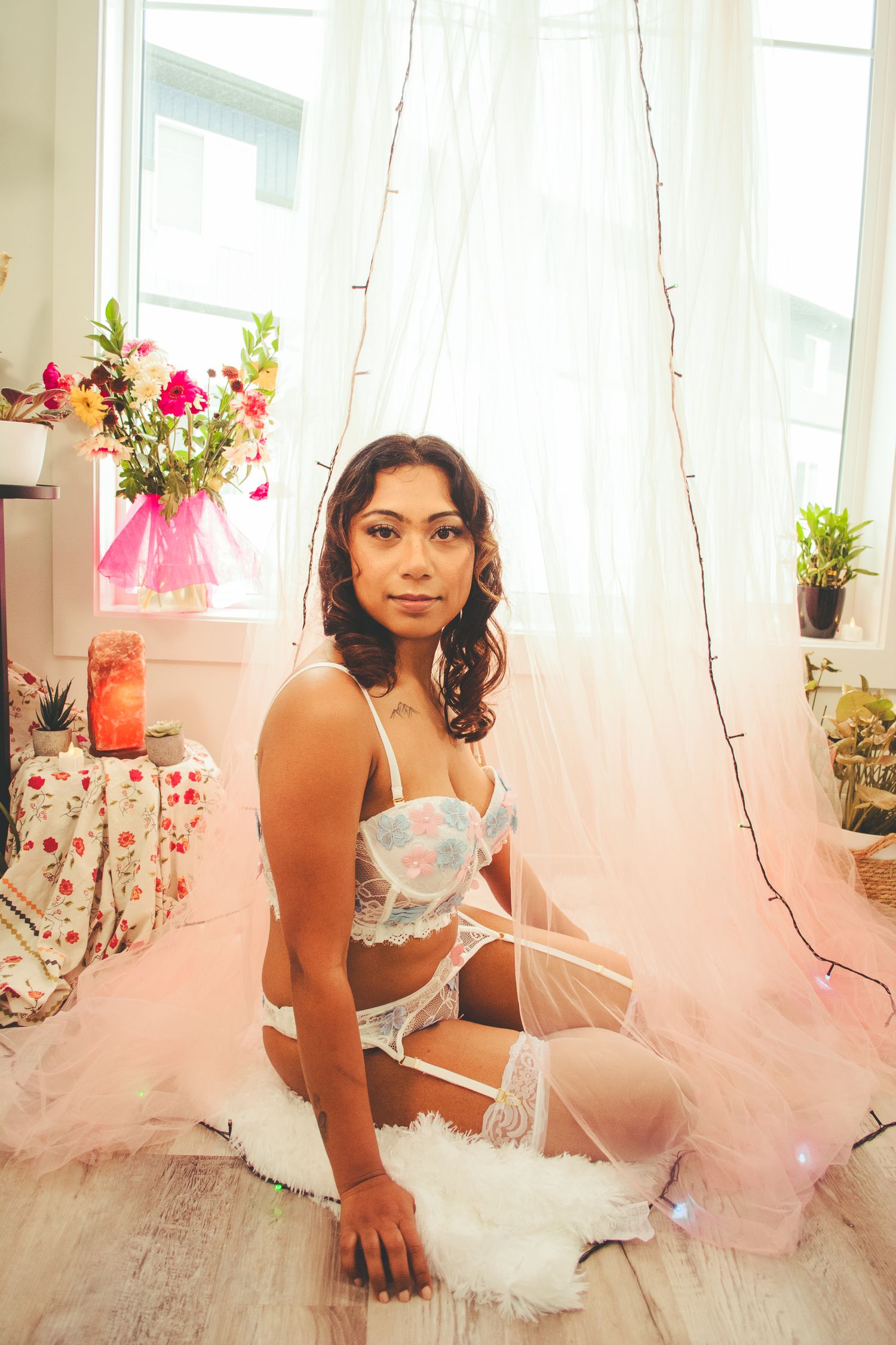 Elegant boudoir photography setup with pink tulle drapery and floral arrangements.