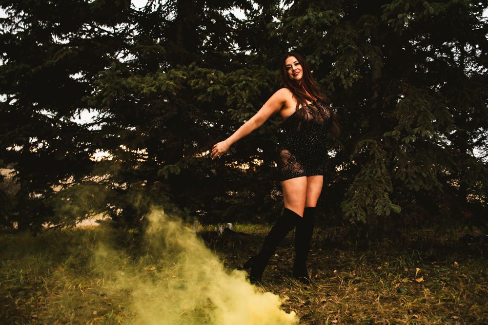 Dynamic fashion shot with yellow smoke effects and evergreen backdrop.