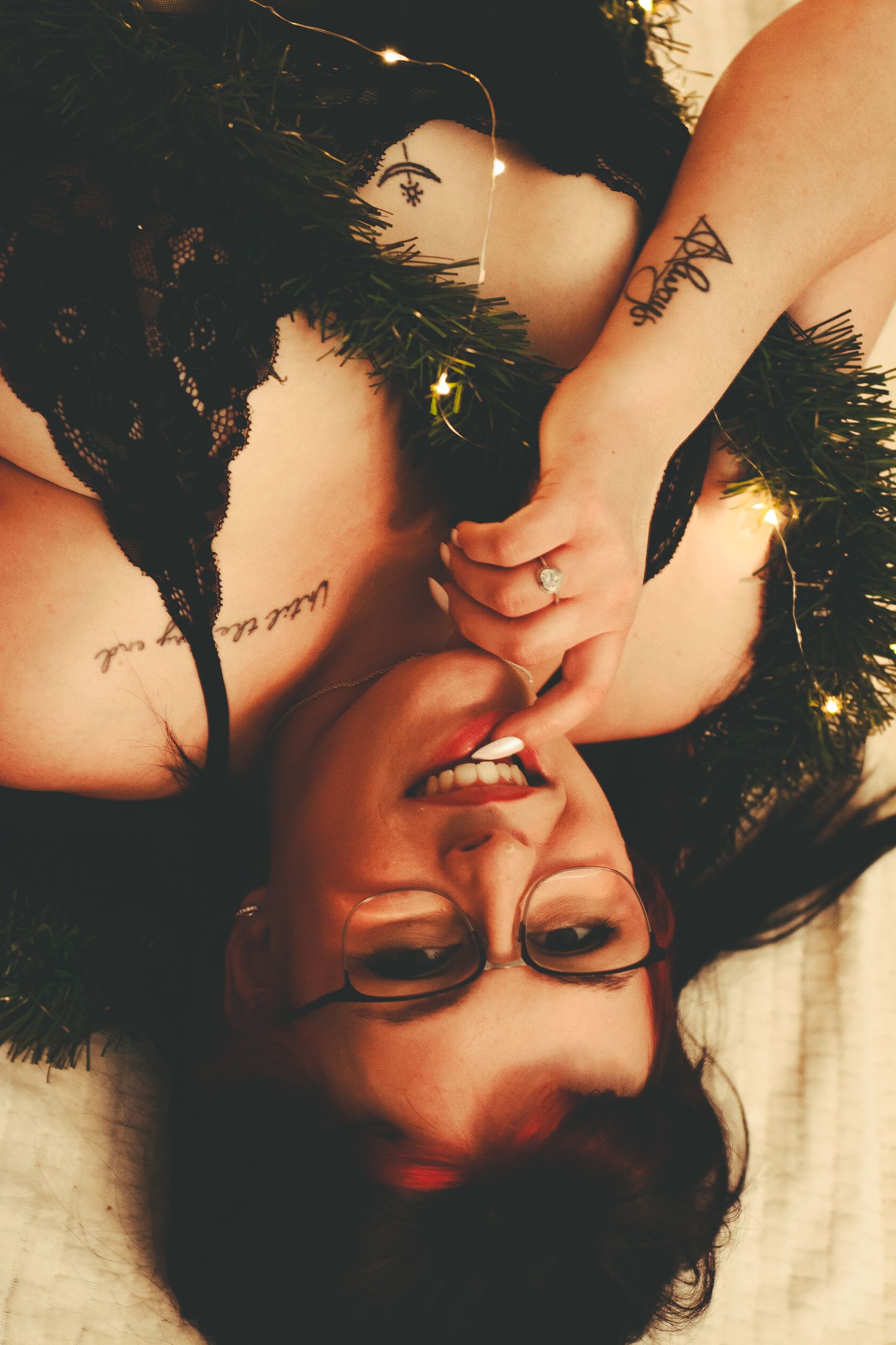 Artistic boudoir photo with black fur trim and twinkling holiday lights creating a festive mood.