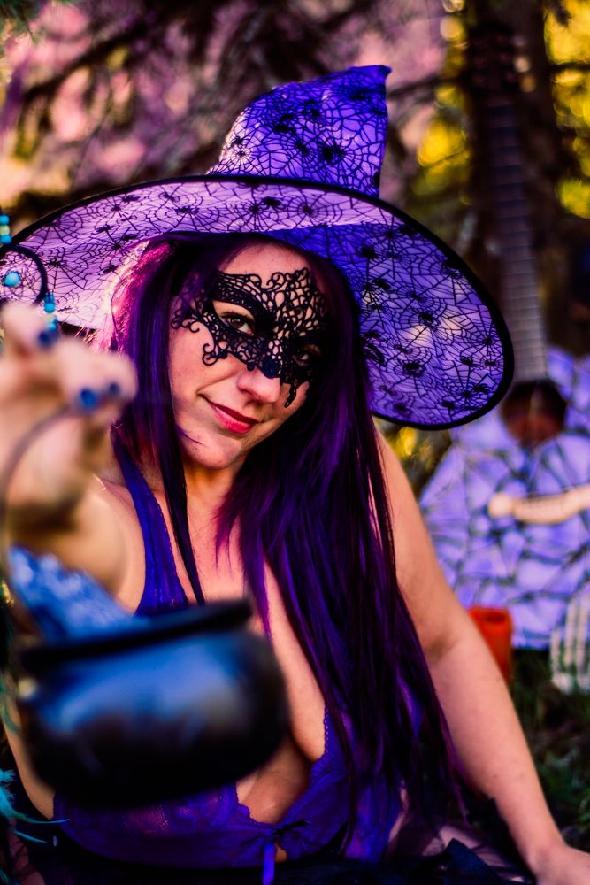 Enchanting Halloween portrait with purple witch hat, lace mask and vibrant autumn colors.