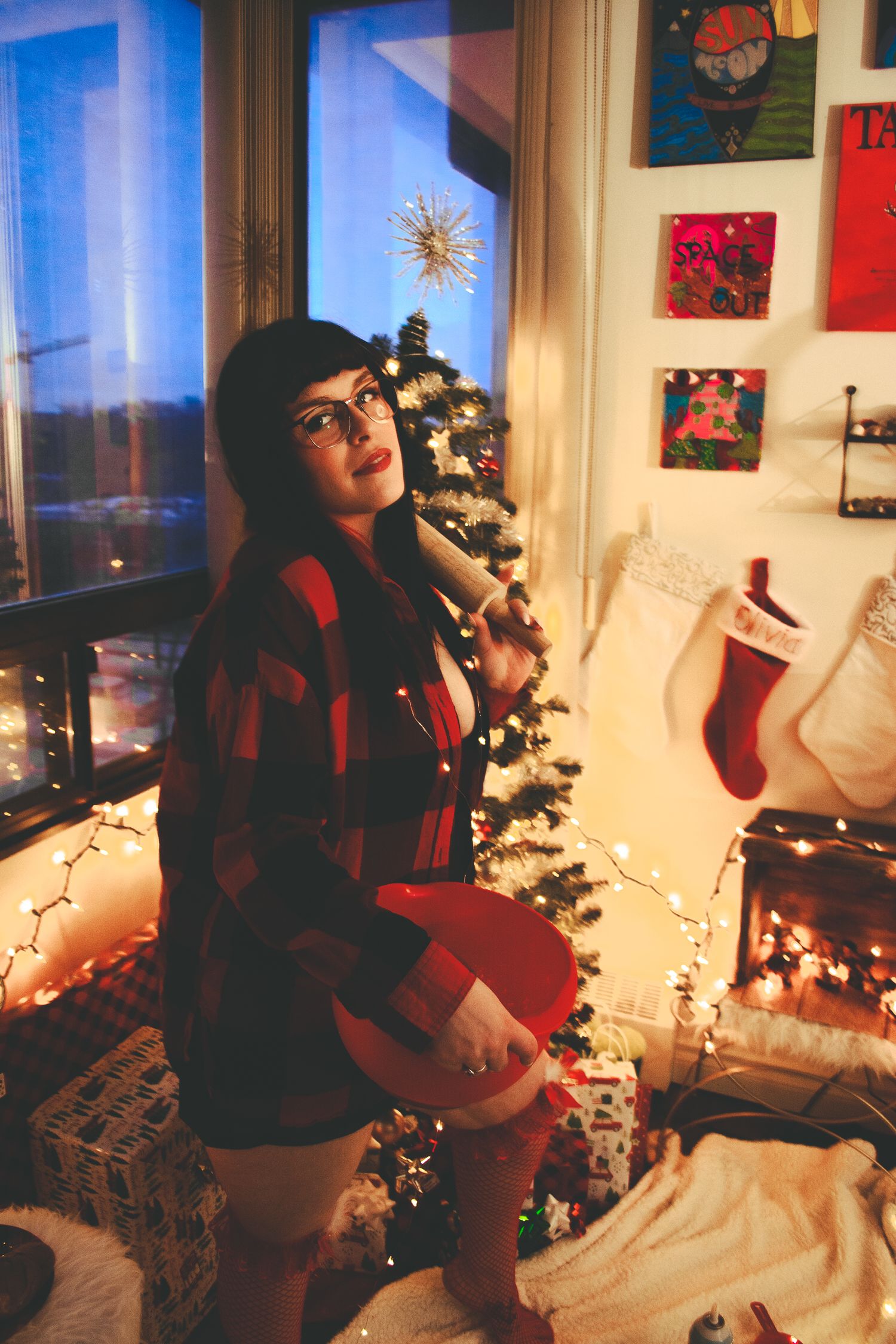 Festive scene with buffalo plaid attire against decorated Christmas tree and city view window.