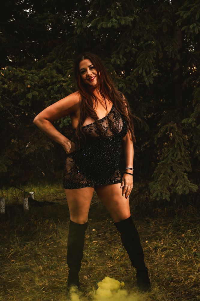 Fashion portrait in black lace and boots with natural forest backdrop.