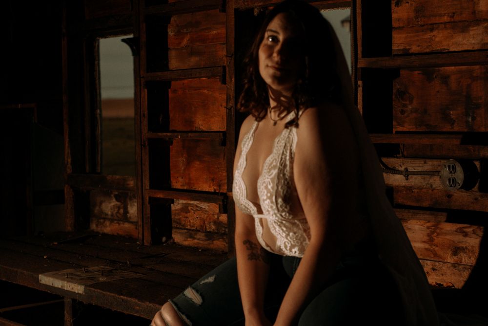 Atmospheric portrait with warm lighting against weathered wooden walls.
