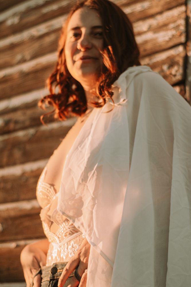 Ethereal bridal portrait bathed in warm sunset light against rustic wooden backdrop.