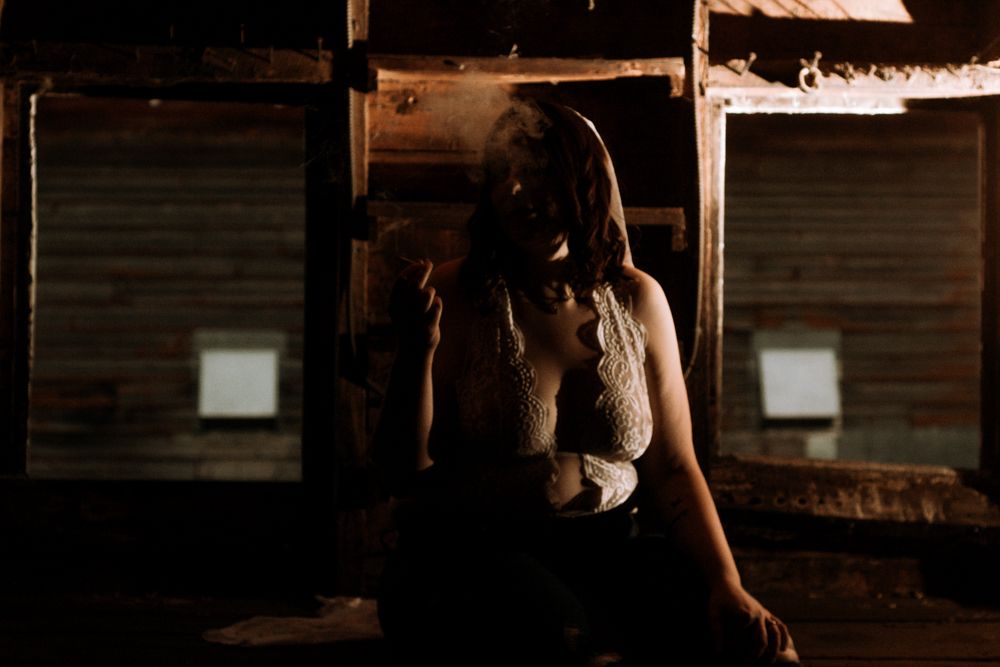 Silhouetted figure posed against vintage wooden panels in dramatic lighting.