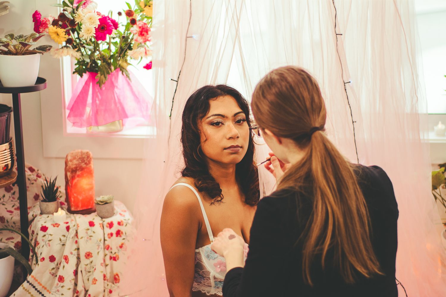 Behind the scenes of a professional makeup application in a pink-decorated studio setting.