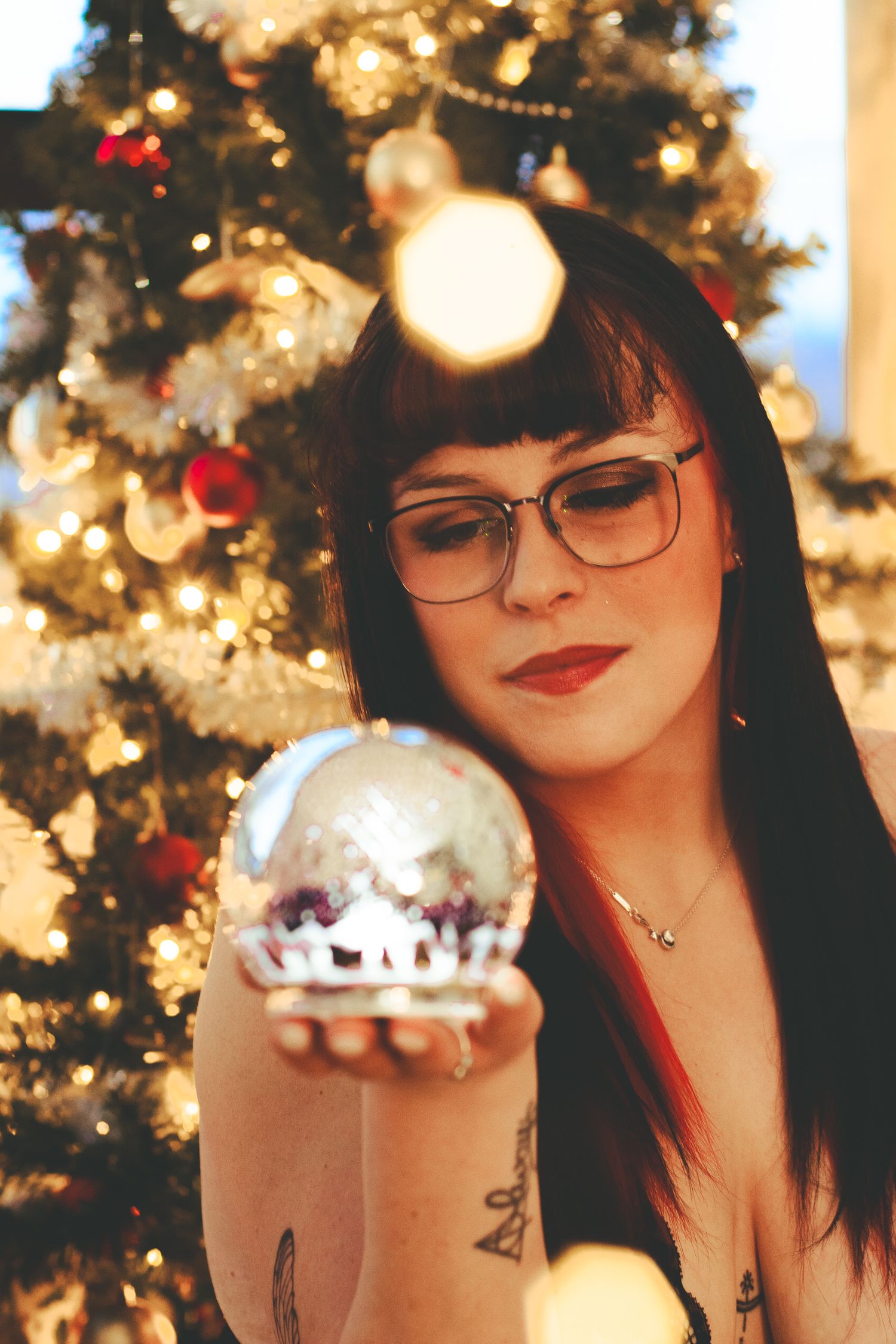 Red and black plaid outfit against backdrop of Christmas tree and holiday decor.
