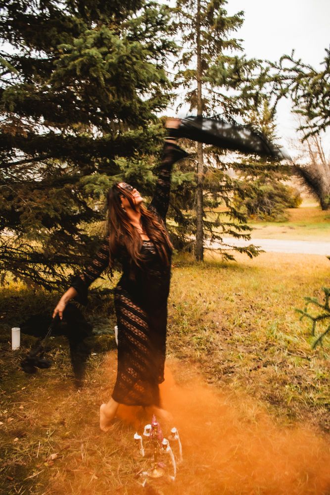 Artistic portrait in nature with flowing lace dress and orange smoke effects.
