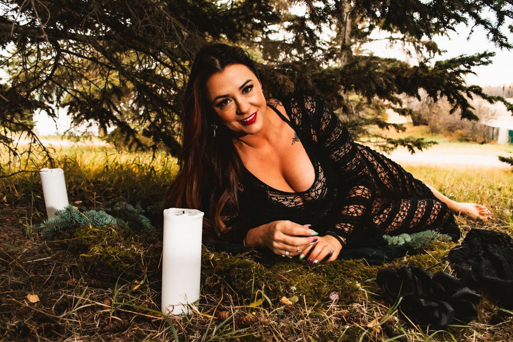 Artistic portrait in black lace against natural setting with decorative white candles.