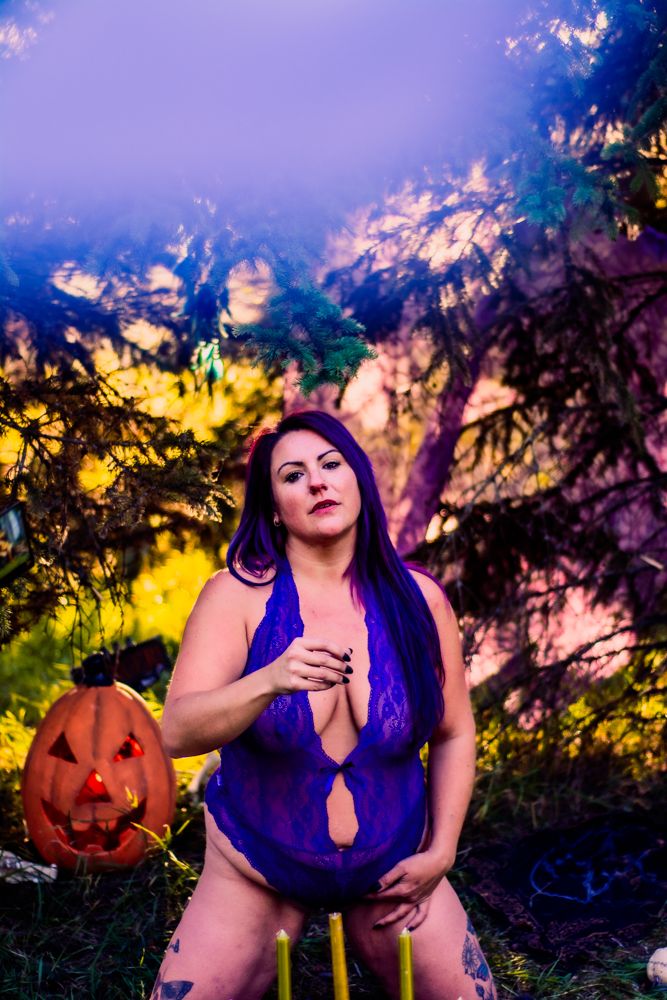 Dramatic outdoor Halloween photoshoot with purple lighting and autumn forest backdrop.