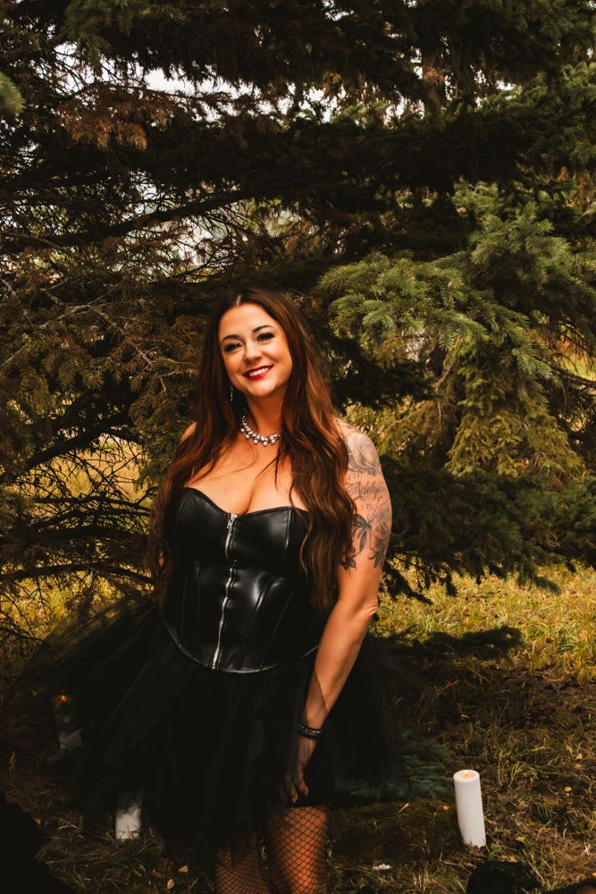 Gothic inspired photo featuring black corset dress and tattoos in forest setting.
