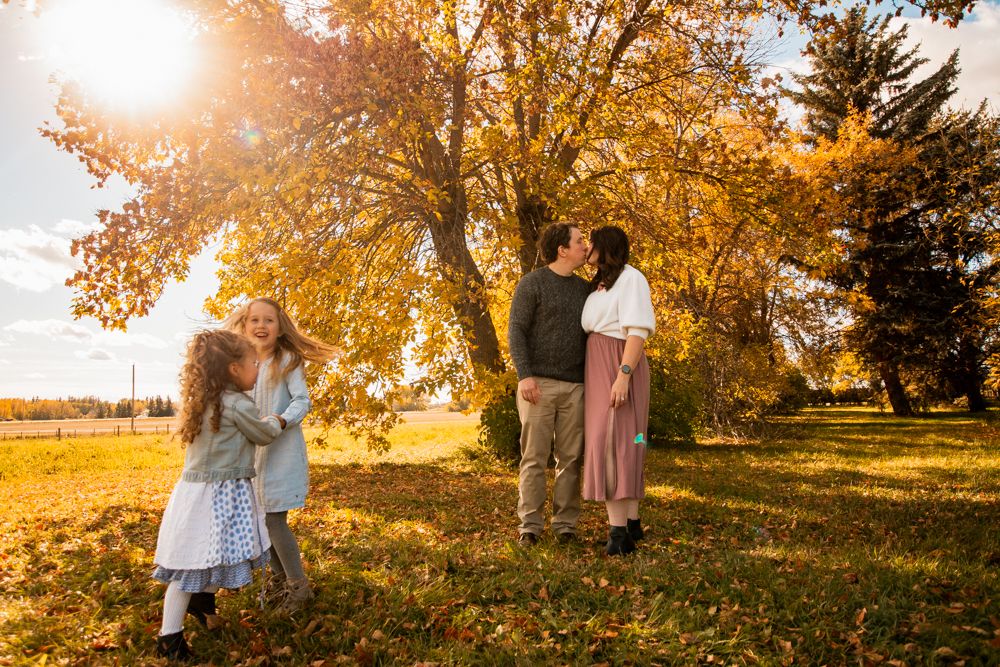 Beautiful autumn scene with golden sunlight streaming through trees as group gathers on fallen leaves.