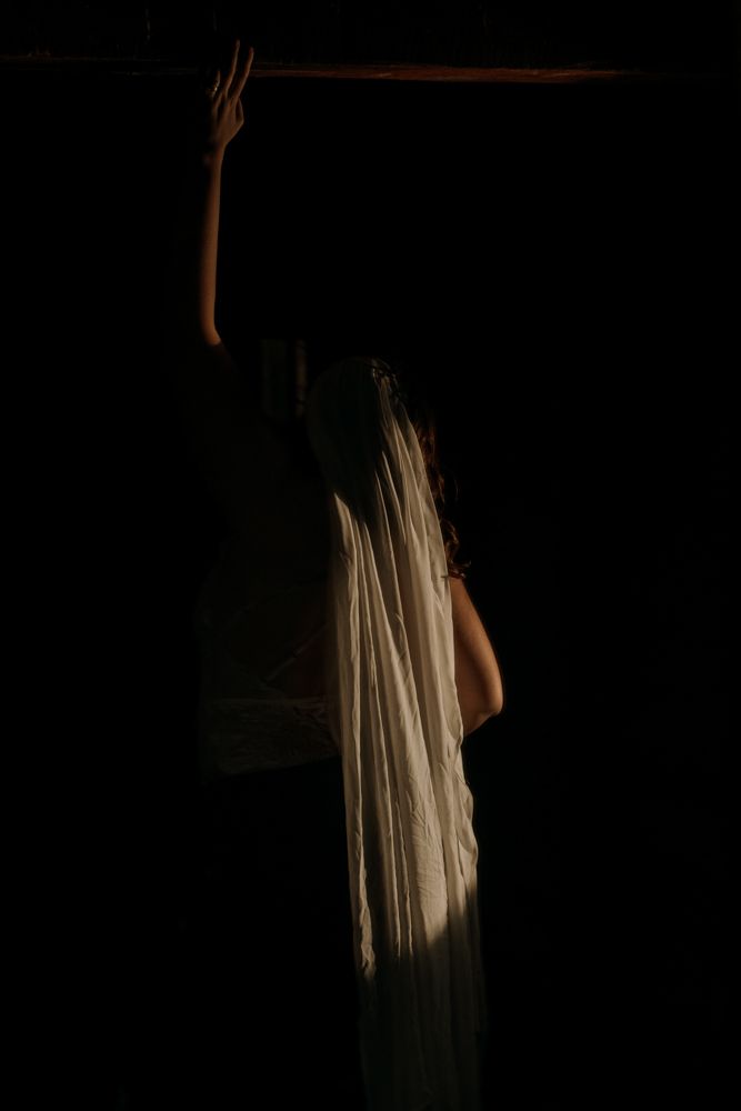 Dramatic silhouette of figure with raised arm against dark background.