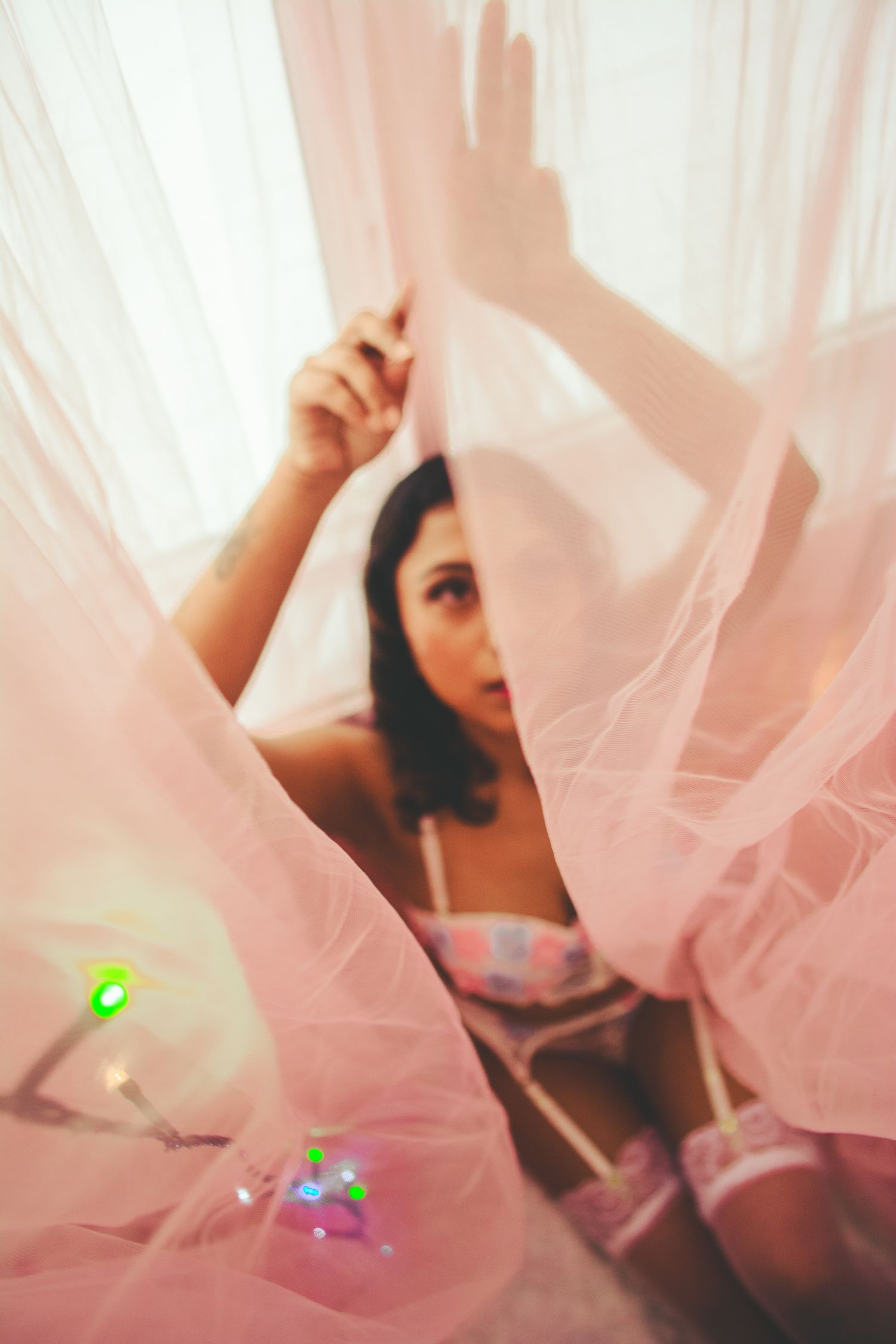 Dreamy boudoir photography with pink tulle and lens flare effects.