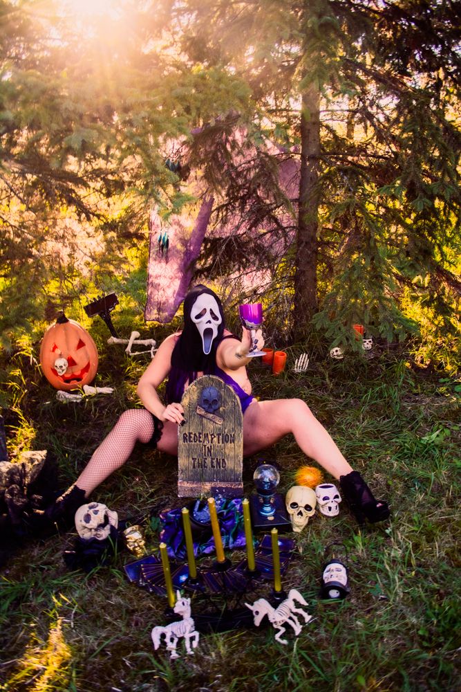Halloween scene with spooky decor featuring pumpkins, skulls, and gravestones in a moody forest setting at sunset.