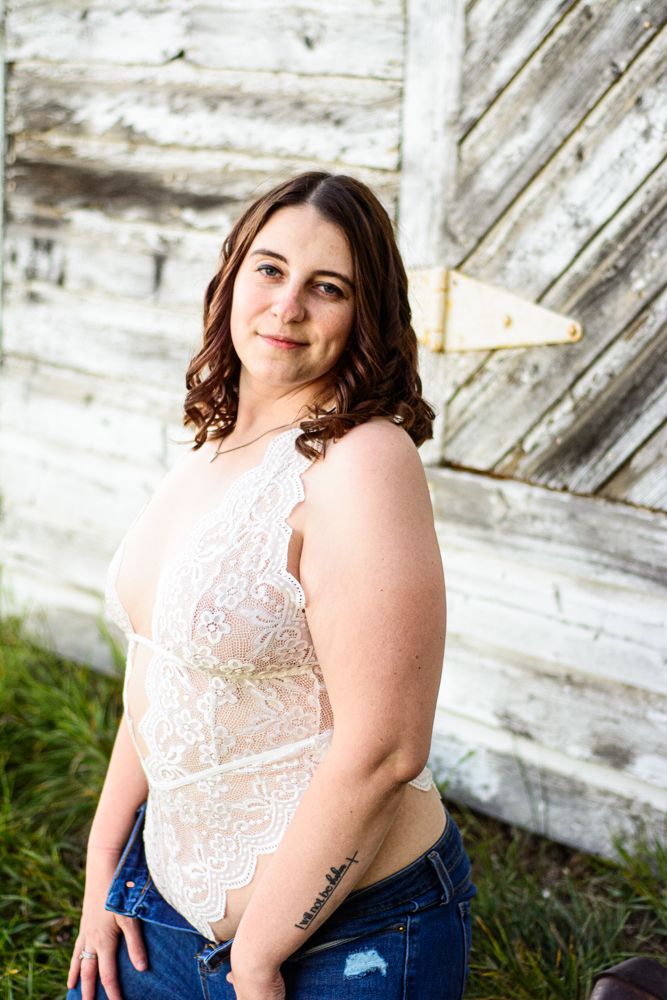 Confident pose in white lace top against diagonal wood planking.