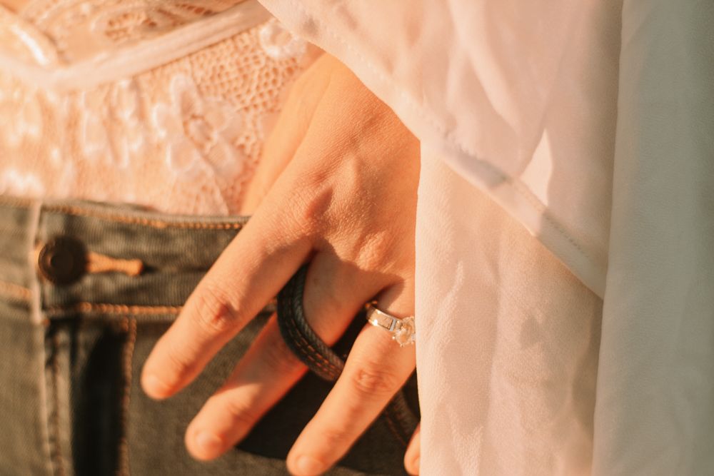 Close-up shot of a hand wearing elegant rings against delicate lace and white fabric.