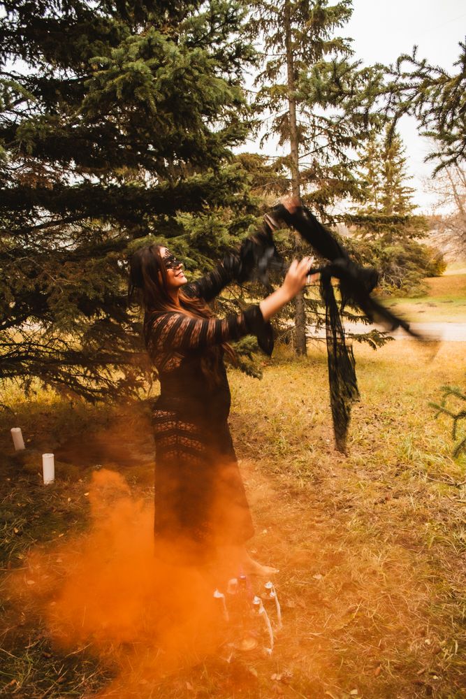 Mystical forest photography with dramatic orange smoke and evergreen trees.