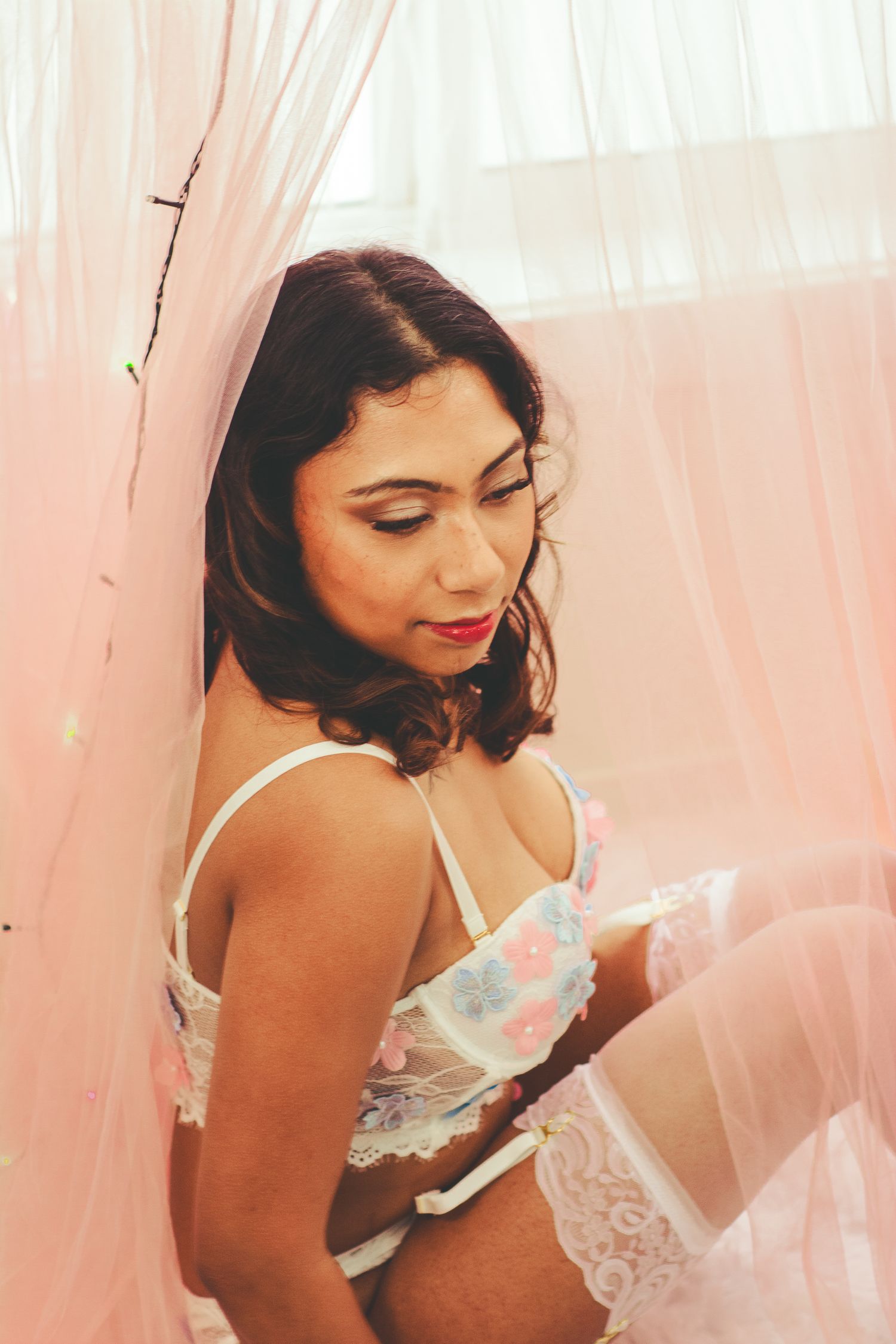 Intimate boudoir photo featuring soft pink tones and delicate lace details.