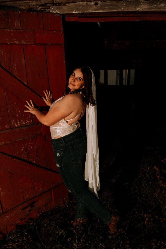 Creative portrait against red barn door in dramatic evening lighting.