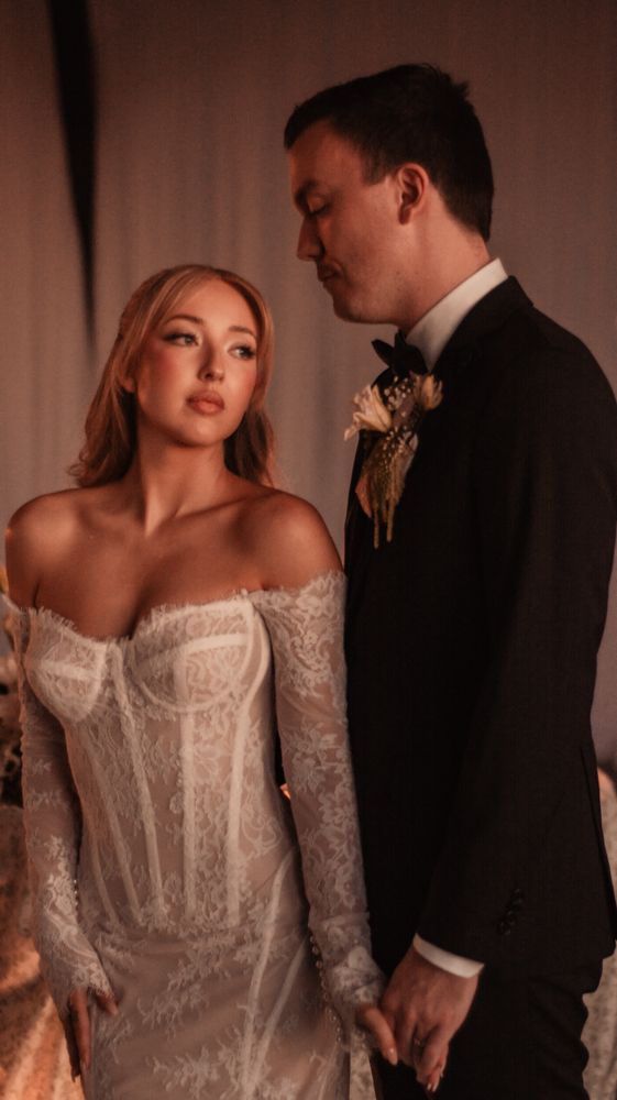 Romantic wedding couple in formal attire illuminated by warm ambient lighting.