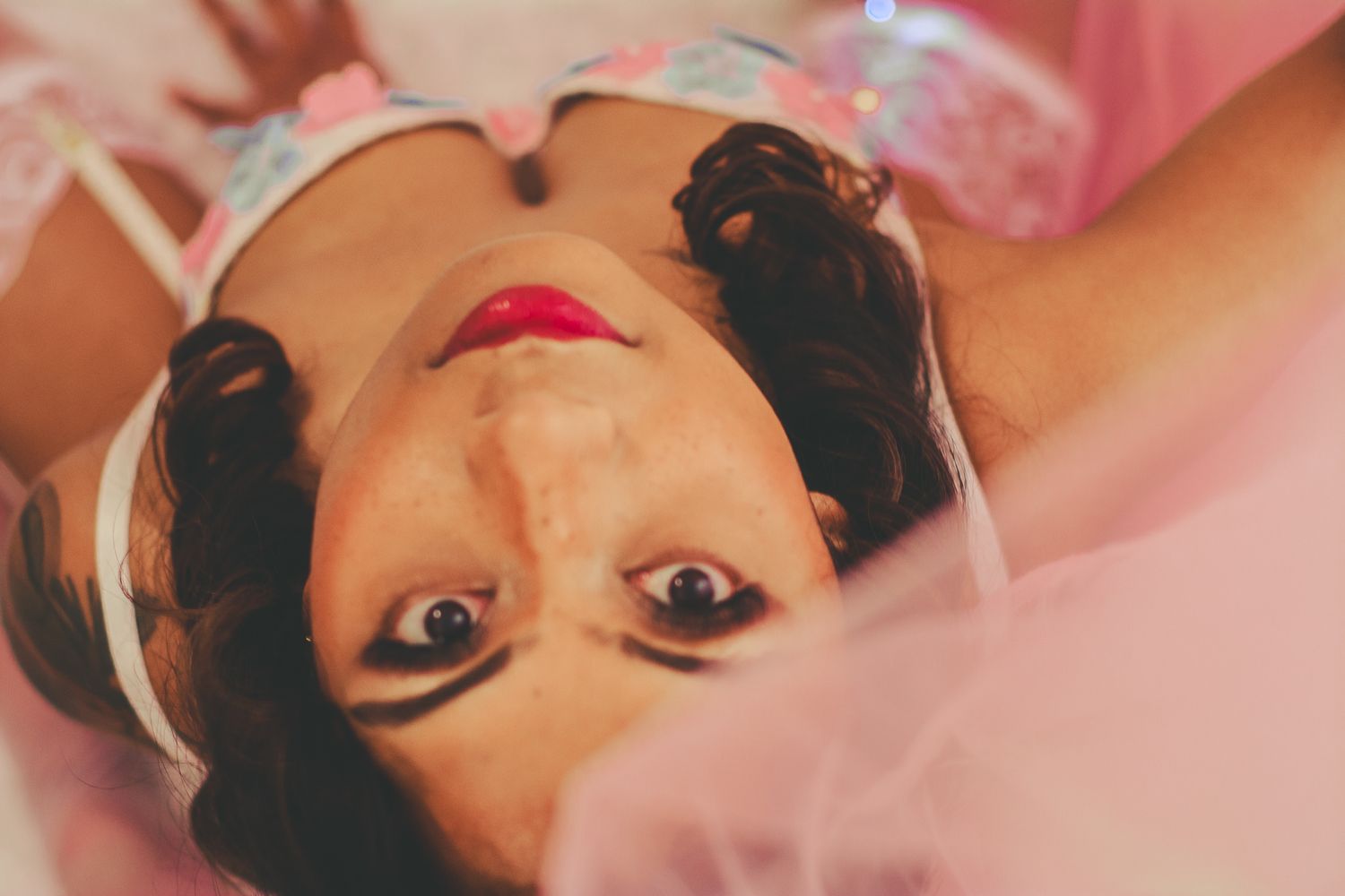 Artistic overhead portrait with pink tulle and soft romantic lighting.