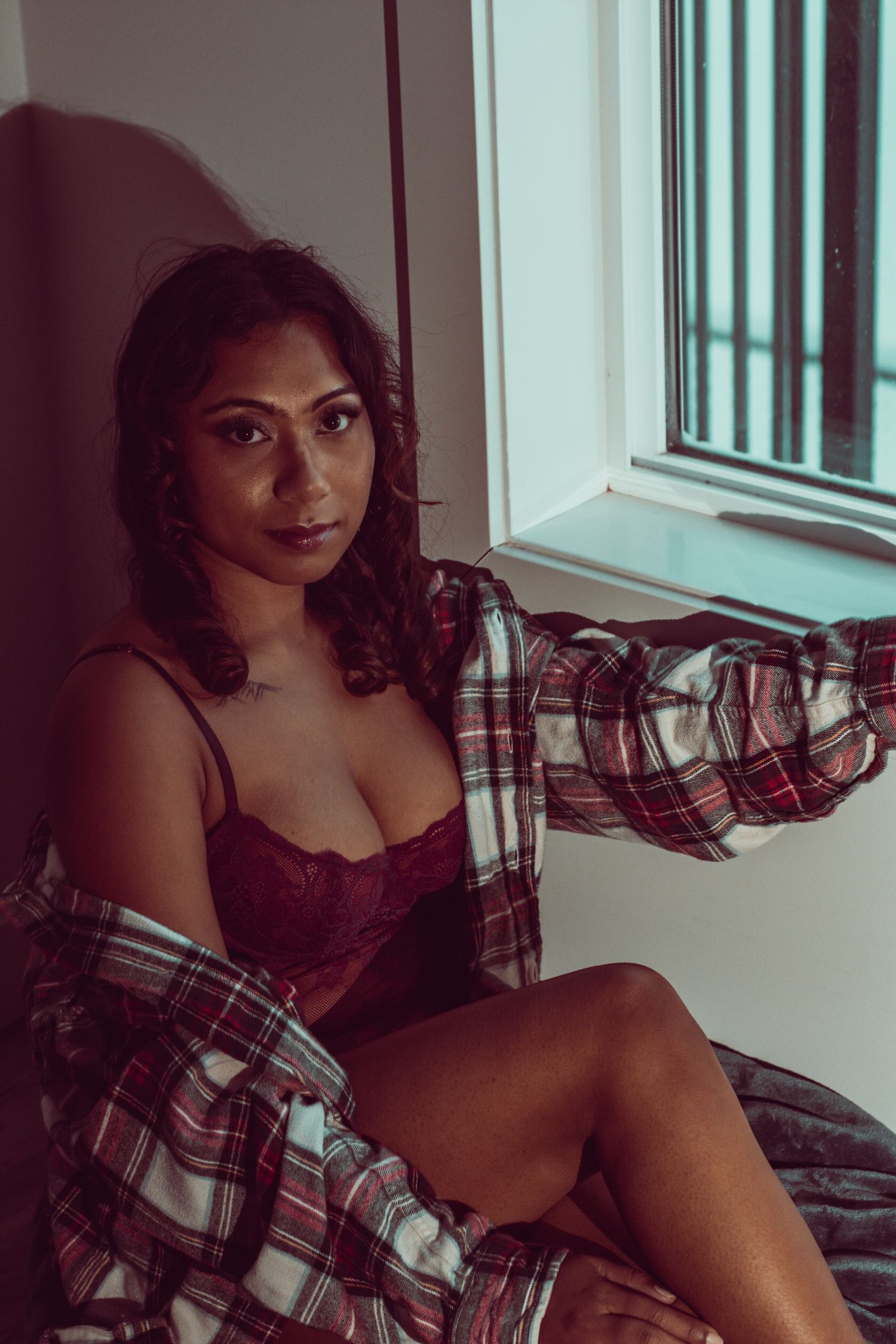 Intimate portrait against window with dramatic lighting and plaid shirt styling.