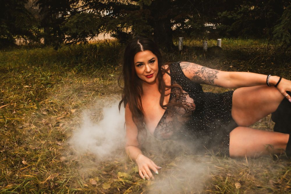 Creative photo shoot on grass with atmospheric smoke effects.