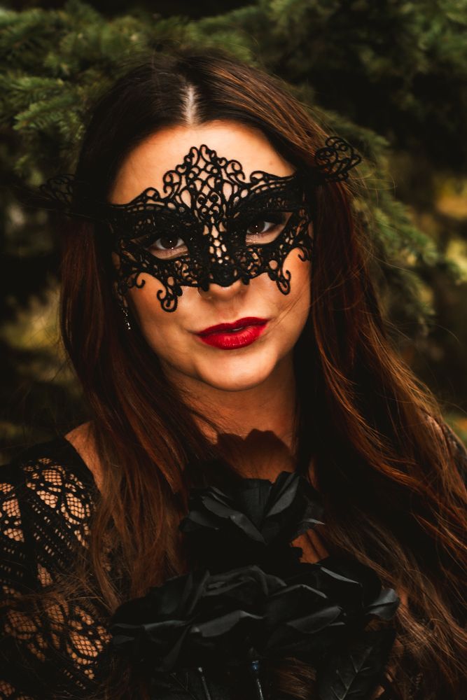 Elegant portrait featuring ornate black lace mask and bold red lips.