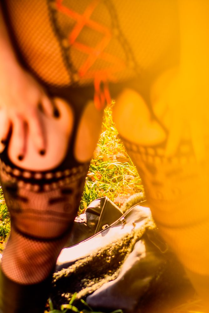 Abstract close-up of fishnet stockings with autumn leaves in background.