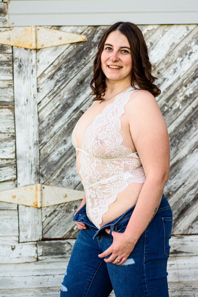 Fashion portrait showcasing white lace bodysuit against rustic wooden background.