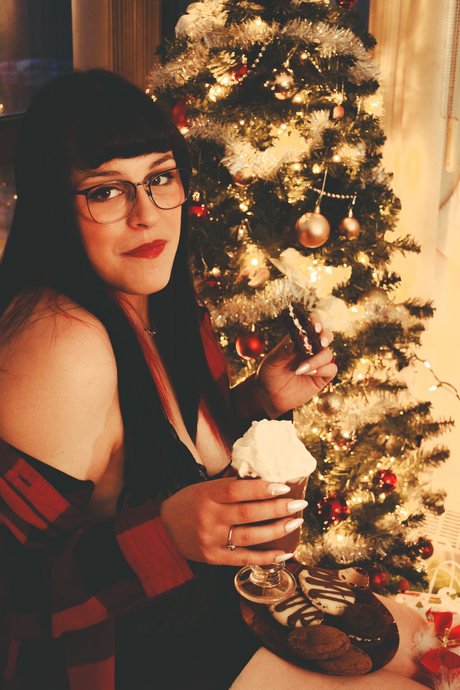 Warm holiday setting with treats and a decorated Christmas tree glowing in soft lighting.