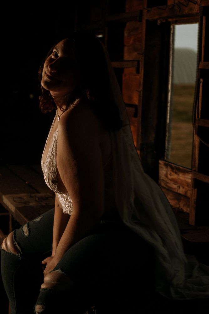 Artistic silhouette portrait against rustic window with warm backlighting.