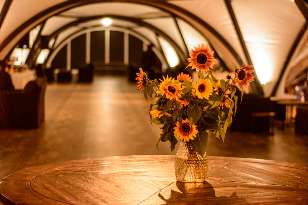 Rustic wooden table with sunflower centerpiece in warm ambient lighting.