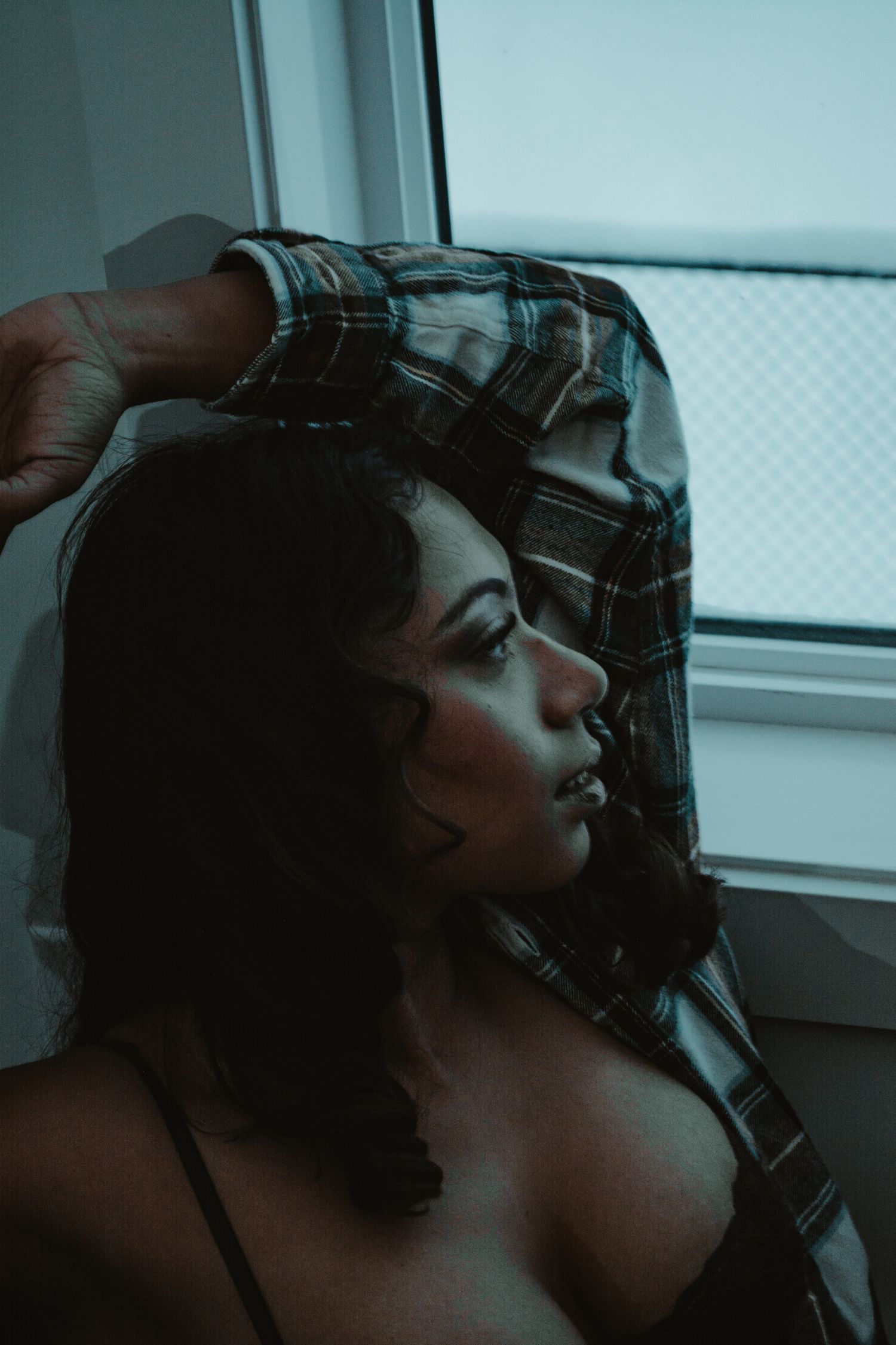 Moody close-up portrait with plaid fabric and dramatic lighting.